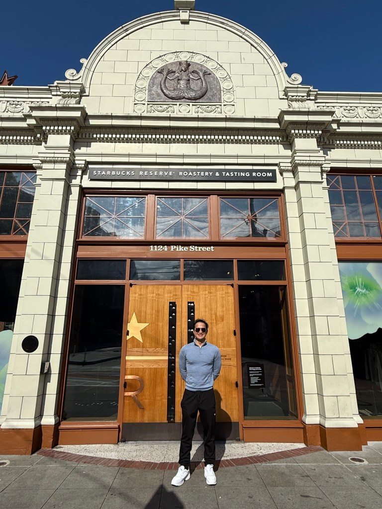 A person standing in front of the Starbucks Reserve Roastery and Tasting Room on Pike Street in Seattle, showcasing the building's architectural details.